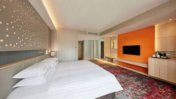 Ein Hotelzimmer mit einem großen Bett, einem Fernseher, einem Schreibtisch und moderner Einrichtung.