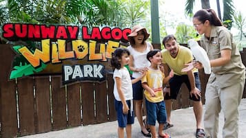 A family at Sunway Lagoon Wildlife Park, standing in front of a wooden fence with a sign.