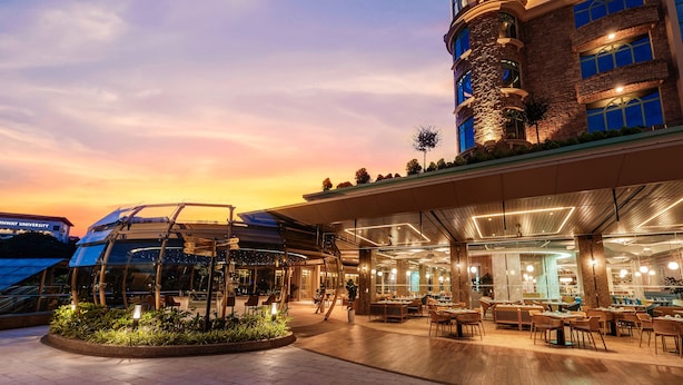 A hotel with a modern design, featuring a covered outdoor area with seating and a glass facade.