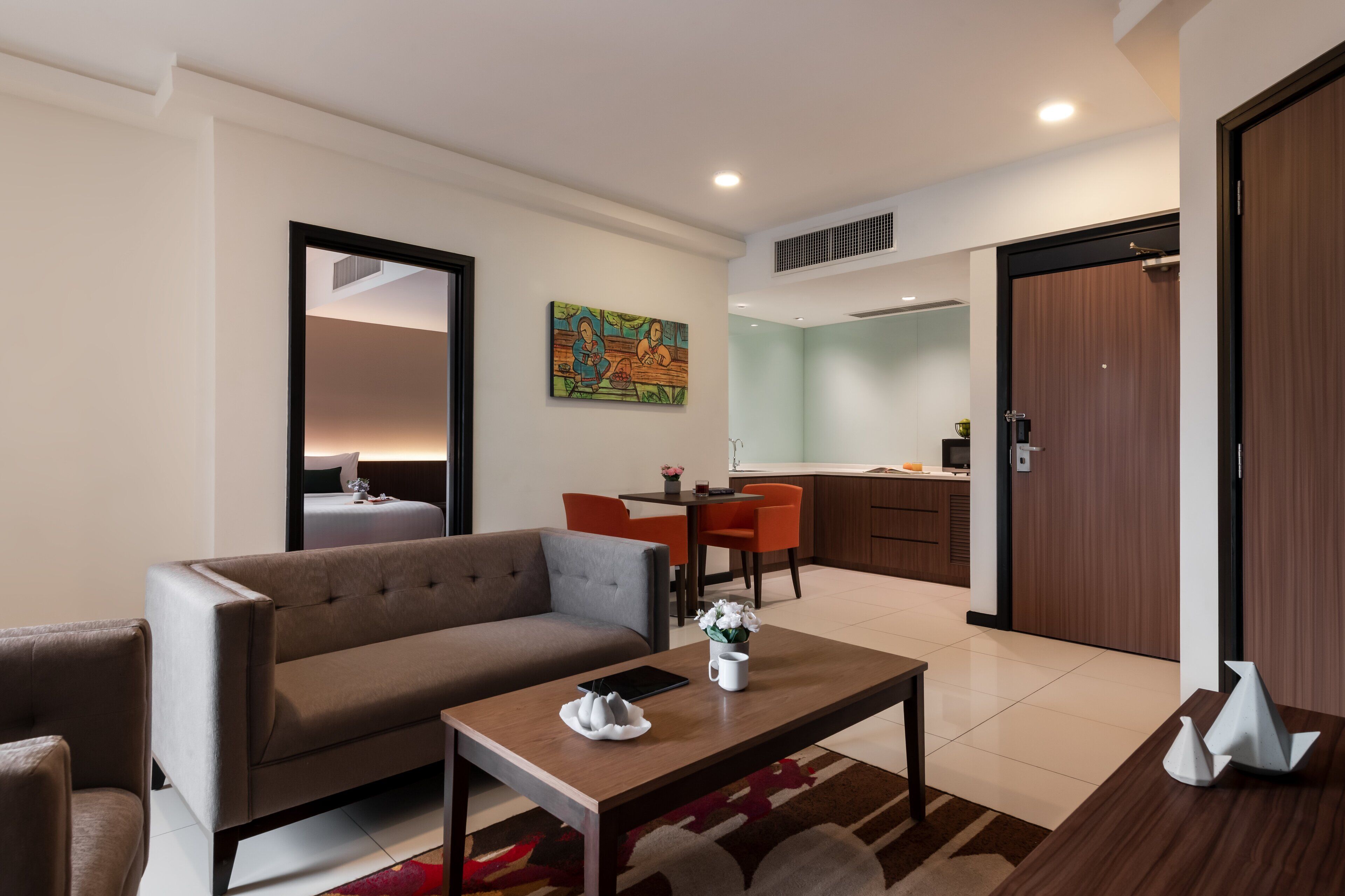 Una sala moderna con un sofá, una mesa de centro y un comedor. Se ve una cocina al fondo con una mesa y sillas.
