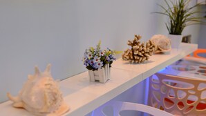 A shelf with decorative items including a seashell, a potted plant, and a vase with flowers. - Shell Hotel (Hengchun)