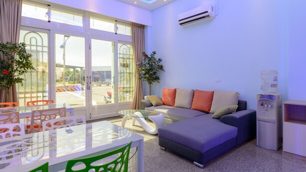 A modern living room with a glass dining table, a sofa, and a water dispenser. - Shell Hotel (Hengchun)