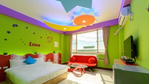 A brightly colored hotel room with a bed, a red sofa, a glass coffee table, and a TV. - Shell Hotel (Hengchun)