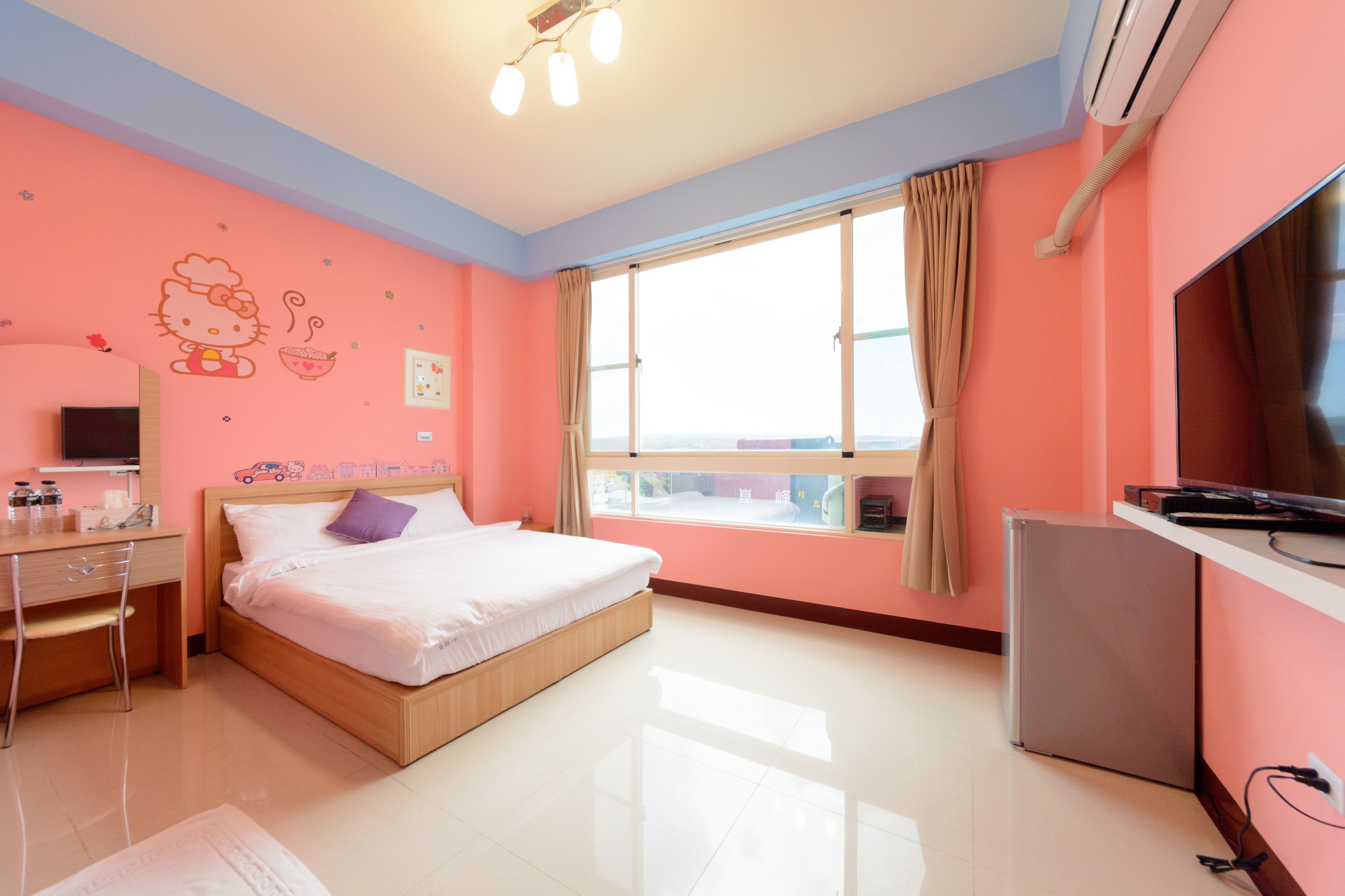 Un dormitorio con cama, escritorio, televisor y ventana con cortinas.