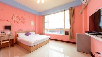 Un dormitorio con cama, escritorio, televisor y ventana con cortinas.