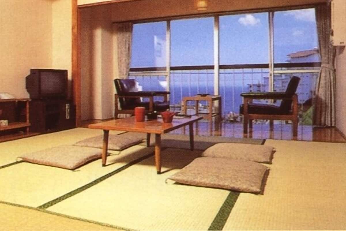 A traditional tatami mat room with a low table, two chairs, and a television.