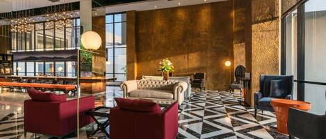 En moderne lobby med et skakternet gulv, siddepladser og en bar.