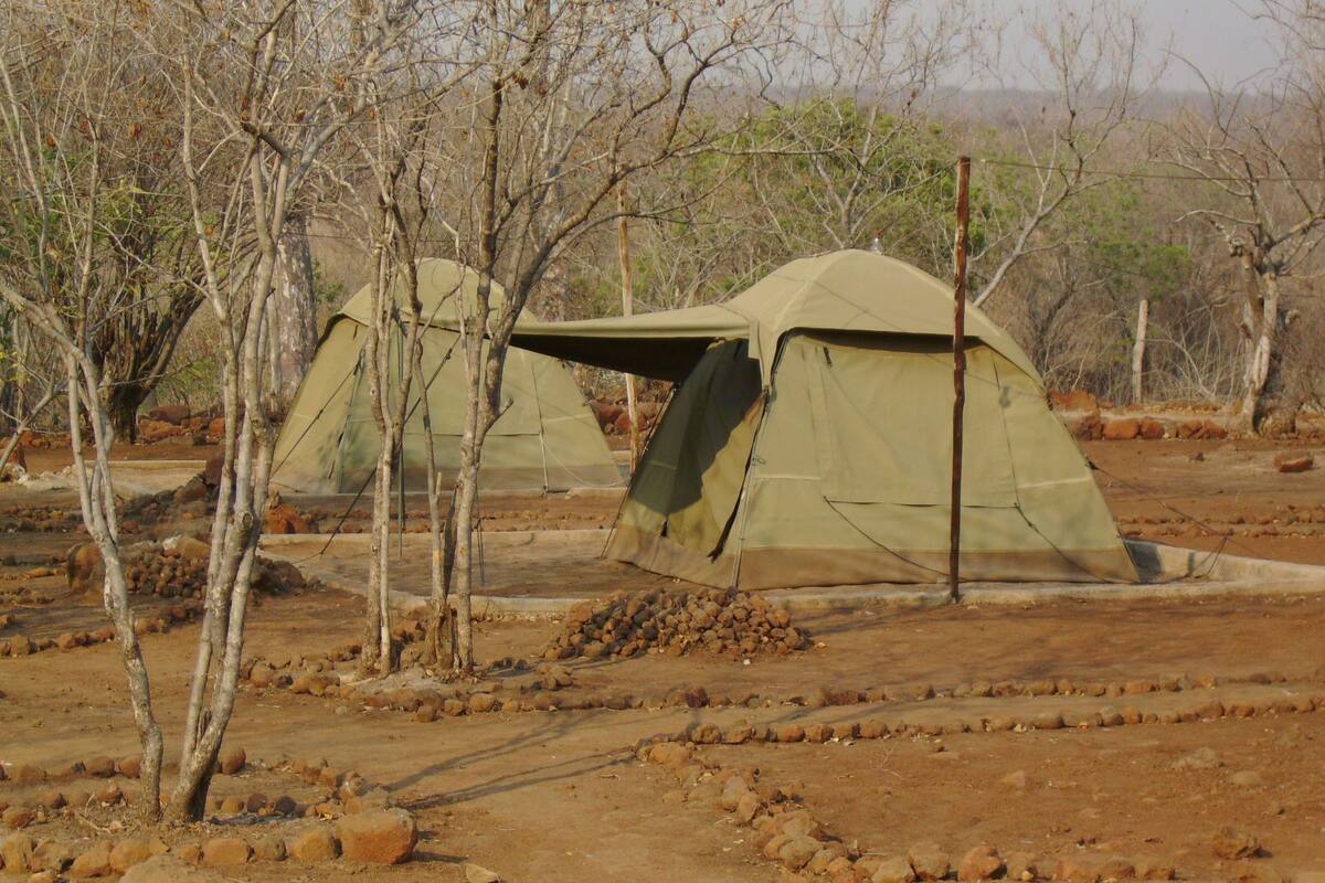Two tents in a dry, rocky terrain with sparse vegetation.