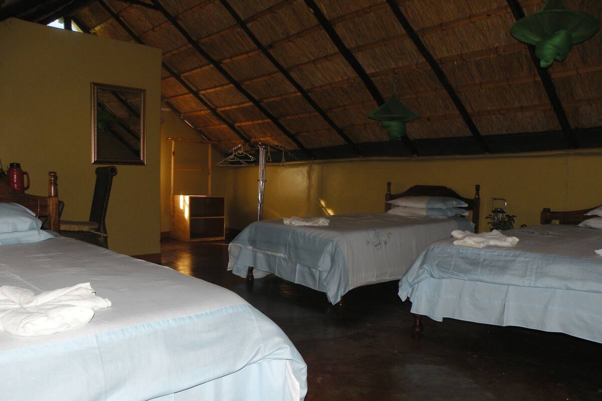 A hotel room with two beds, a wooden ceiling, and a framed picture on the wall.