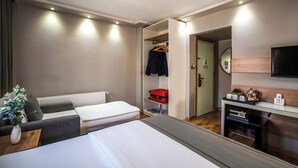 A hotel room with a bed, a sofa, a desk with a mirror, and a walk-in closet. - My Dora Hotel (Istanbul)