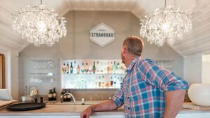 A bar area with a counter, two chandeliers, and a sign above the bar. - Löderups Strandbad Hotell & Stugby (Loderup)