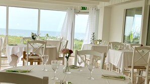A dining area with round tables, white tablecloths, and chairs. Each table has a vase with flowers and wine glasses. - Löderups Strandbad Hotell & Stugby (Loderup)