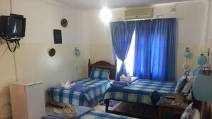 A room with two beds, a small table, a TV, and an air conditioner. - Liya Guest Lodge (Kasane)
