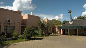 A building with a flat roof and a small structure with a thatched roof. - Liya Guest Lodge (Kasane)
