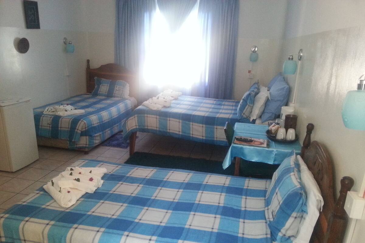A room with two beds, a small table, and a window with curtains.