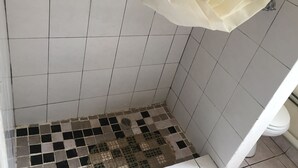 A bathroom with white tiled walls, a checkered floor, and a toilet. - Liya Guest Lodge (Kasane)