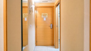 A hotel hallway with wooden doors, a light-colored floor, and a ceiling with recessed lighting.