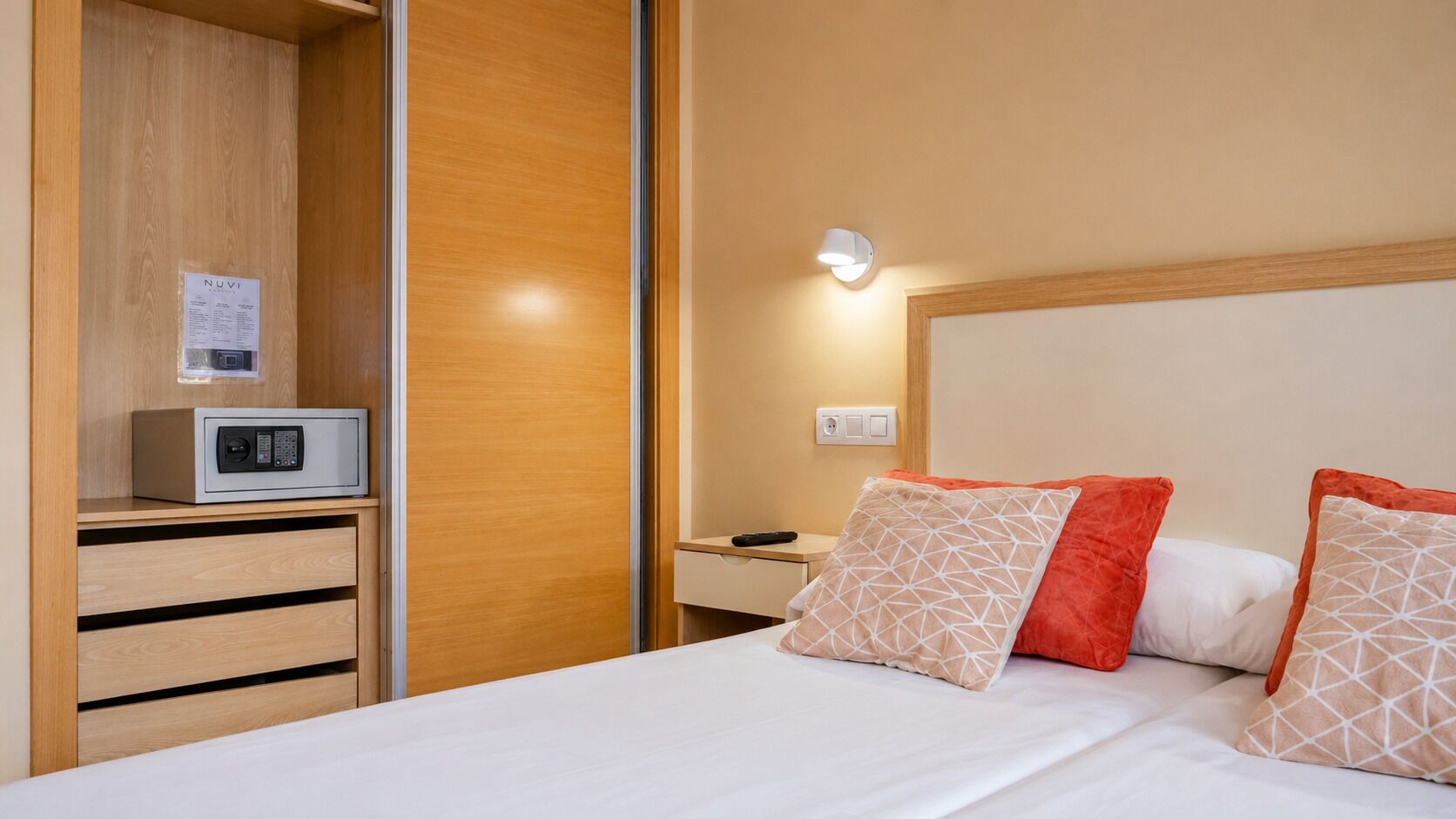 Ein Hotelzimmer mit Bett, Nachttisch, Mikrowelle und Kleiderschrank.