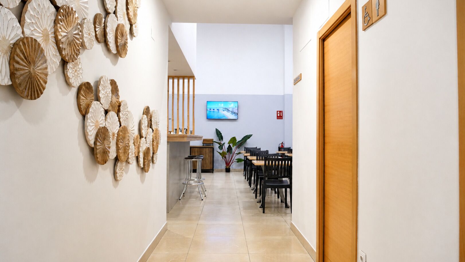 Pasillo de hotel con mostrador de recepción, zona de estar y una pantalla de televisión.