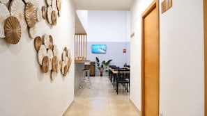 A hotel corridor with a reception desk, seating area, and a television screen.