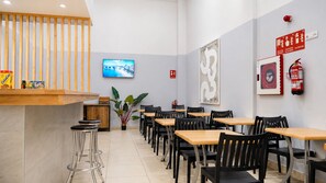 Interior de restaurante con mesas y sillas de madera, barra, pantalla de televisión y equipo de seguridad contra incendios.