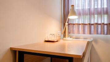 Una mesa de madera con una lámpara de escritorio blanca, un vaso y una caja de pañuelos.