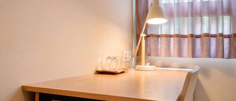 A wooden table with a white desk lamp, a glass, and a tissue box.