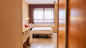 Una habitación de hotel con cama, escritorio y silla.