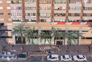 Un edificio de varios pisos con balcones, palmeras y varios letreros, incluyendo 'Clinica Alfonso X el Sabio' y 'Aurea'.
