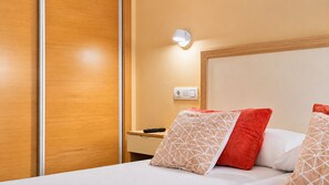 Een hotelkamer met een bed, nachtkastje en een wandlamp.