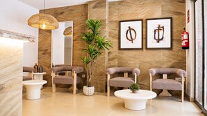 A modern lobby with a reception desk, seating area, and a large mirror. - Nuvi Mercado (Alicante)