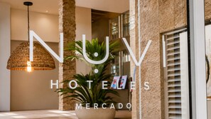 Interior moderno de hotel con una lámpara colgante, una planta en maceta y un cartel en la pared.