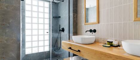 A modern bathroom with a glass-enclosed shower, two sinks, and a large mirror.