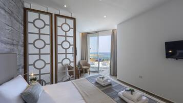 Una habitación de hotel moderna con una cama grande, un balcón con vistas, un televisor y un biombo decorativo.