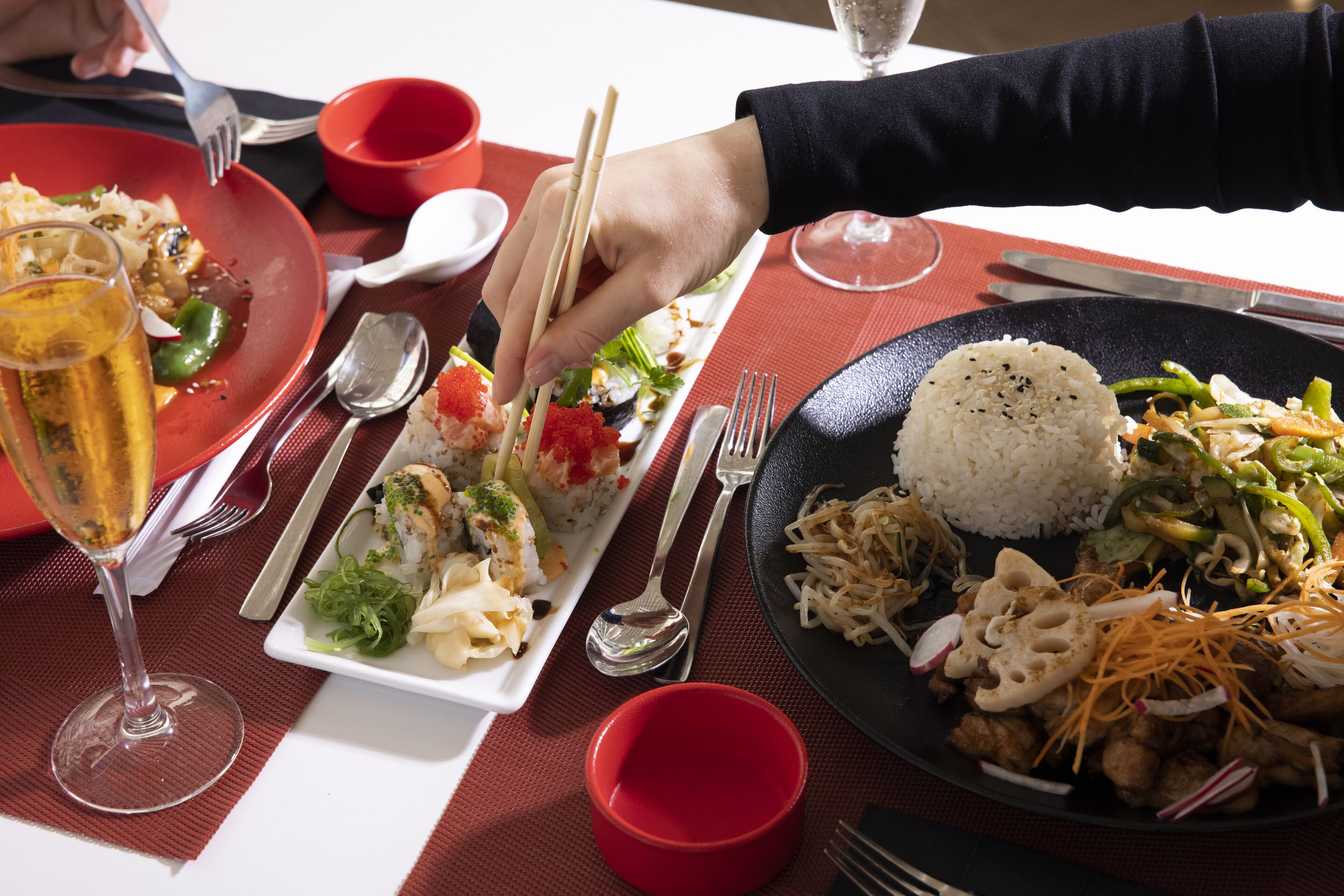 Une table à manger avec différents plats, couverts et un verre de vin.