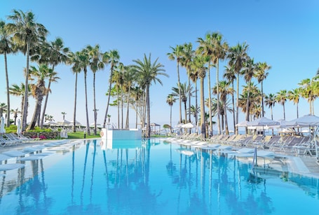 Una piscina techada, una piscina al aire libre, sombrillas
