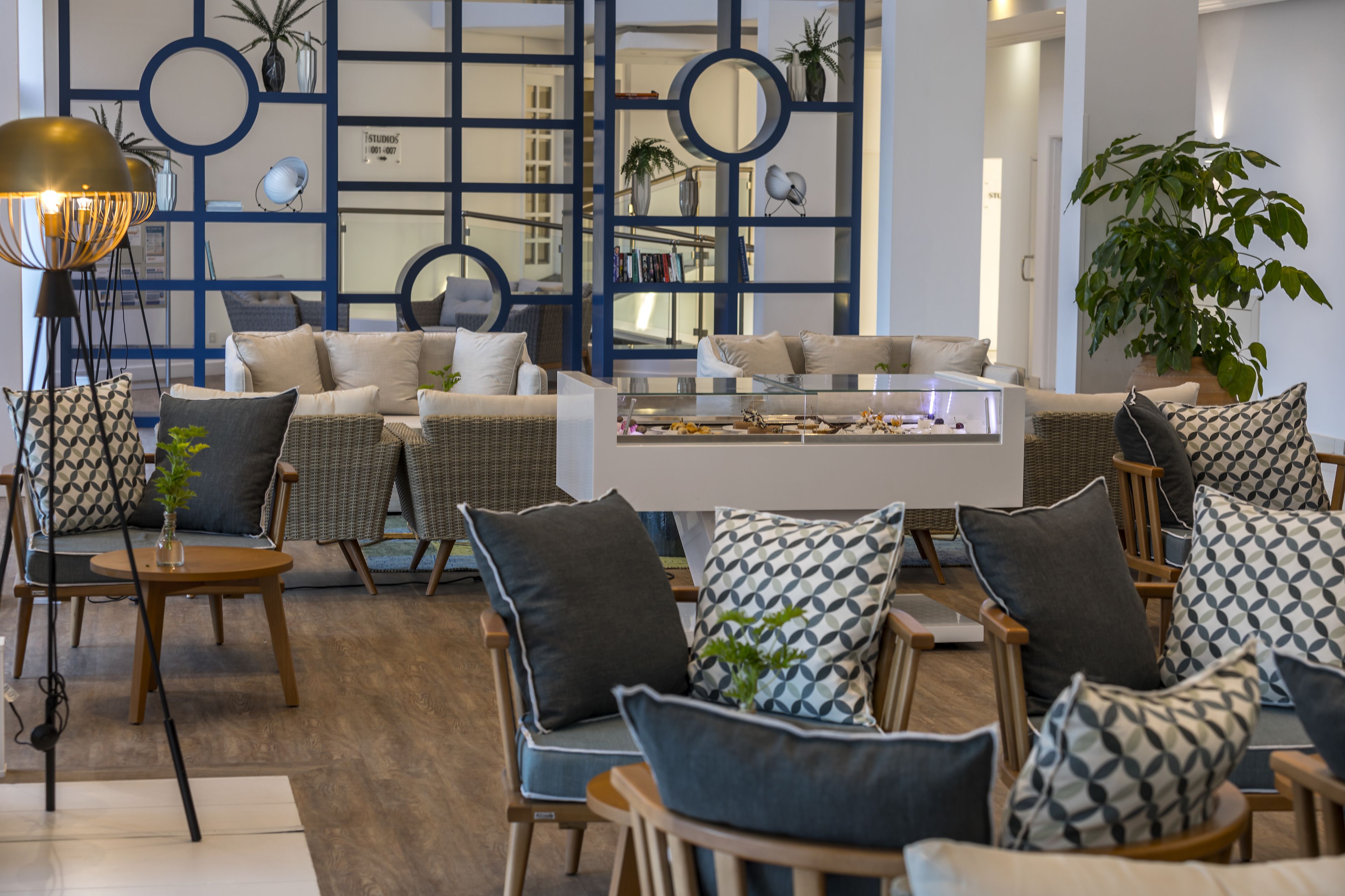 A modern living room with a white coffee table, wicker chairs, and patterned cushions.