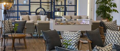 A modern living room with a white coffee table, wicker chairs, and patterned cushions.