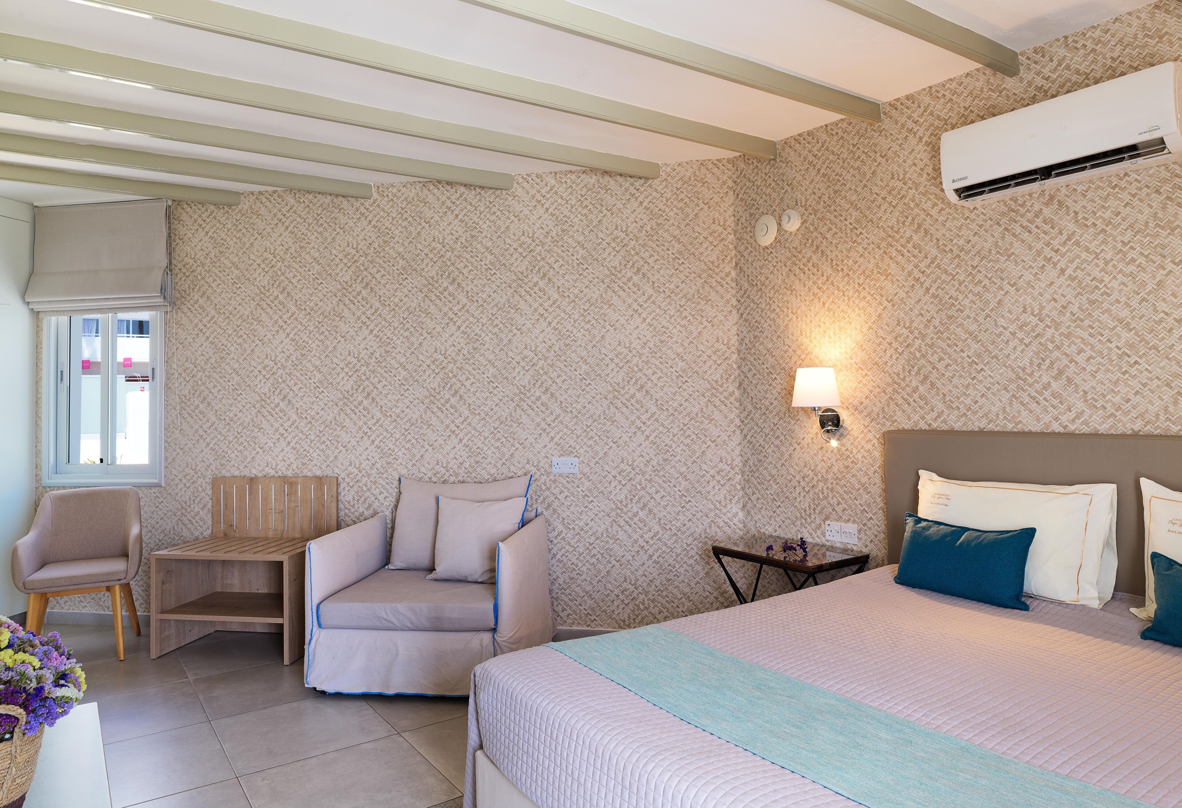 Une chambre d’hôtel équipée d’un lit, d’un canapé, d’une chaise, d’une petite table et d’un appareil de climatisation.