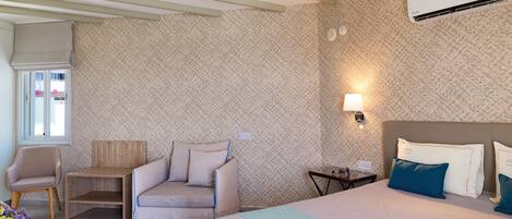 Une chambre d’hôtel équipée d’un lit, d’un canapé, d’une chaise, d’une petite table et d’un appareil de climatisation.