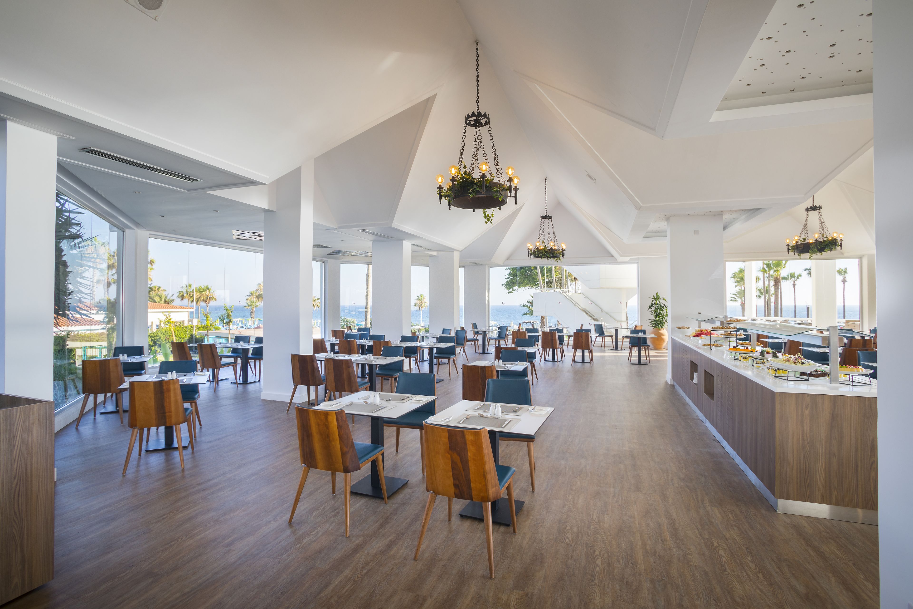 Un comedor espacioso con techos altos, ventanas amplias y candelabros modernos.