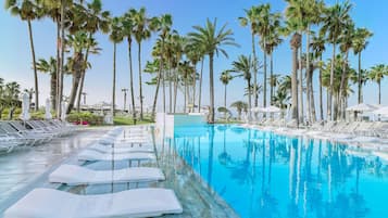 Una piscina techada, una piscina al aire libre, sombrillas