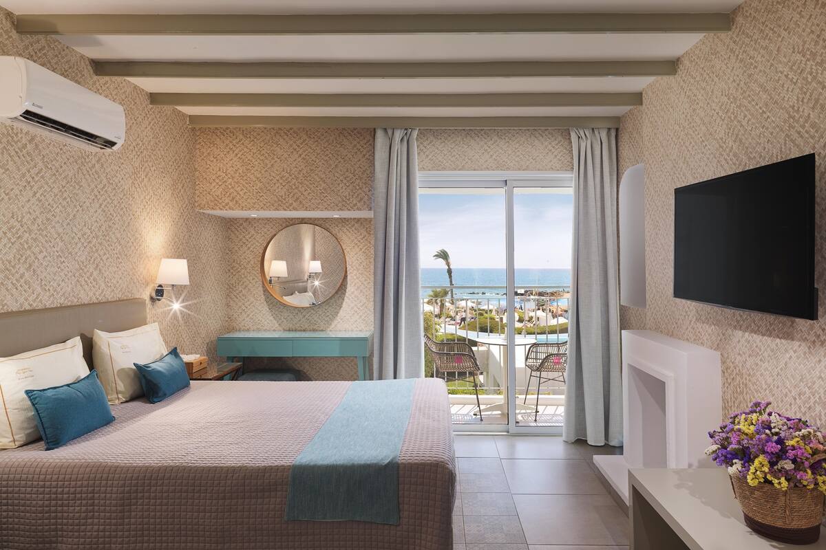 Een hotelkamer met een bed, een televisie, een balkon met uitzicht en een badkamer.