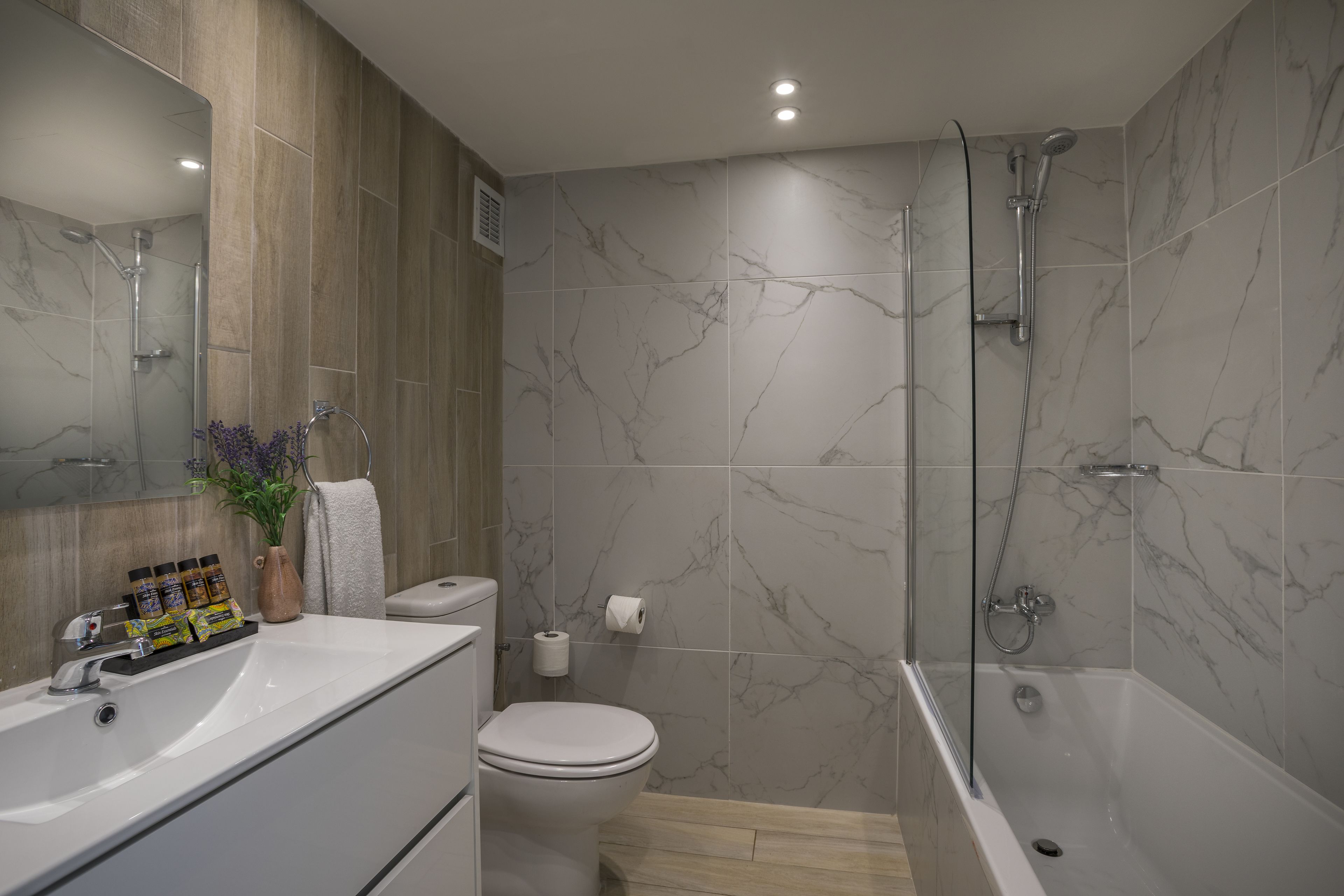 A modern bathroom with a bathtub, shower, toilet, and sink.