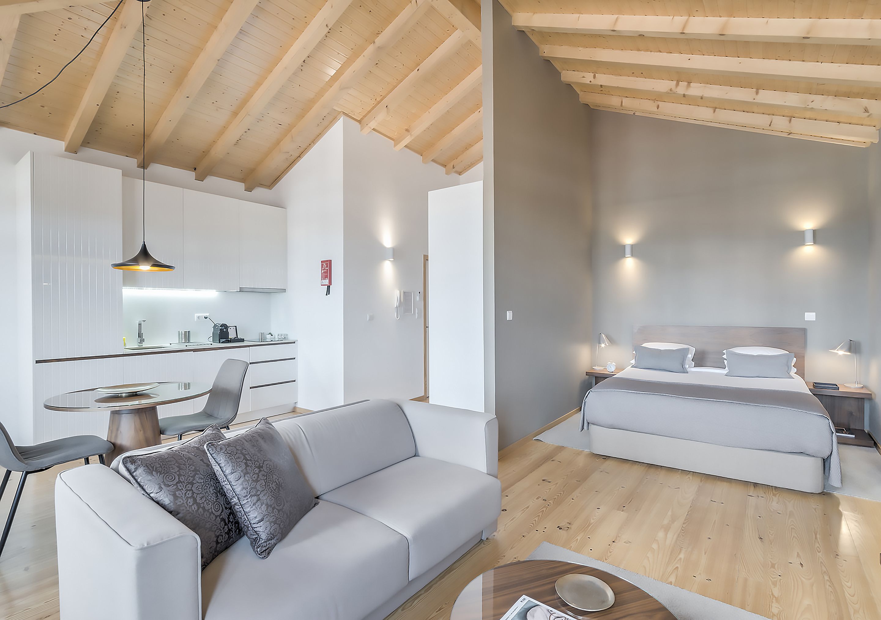 Un interior moderno con zona de comedor, sofá y un dormitorio con cama y mesitas de noche.