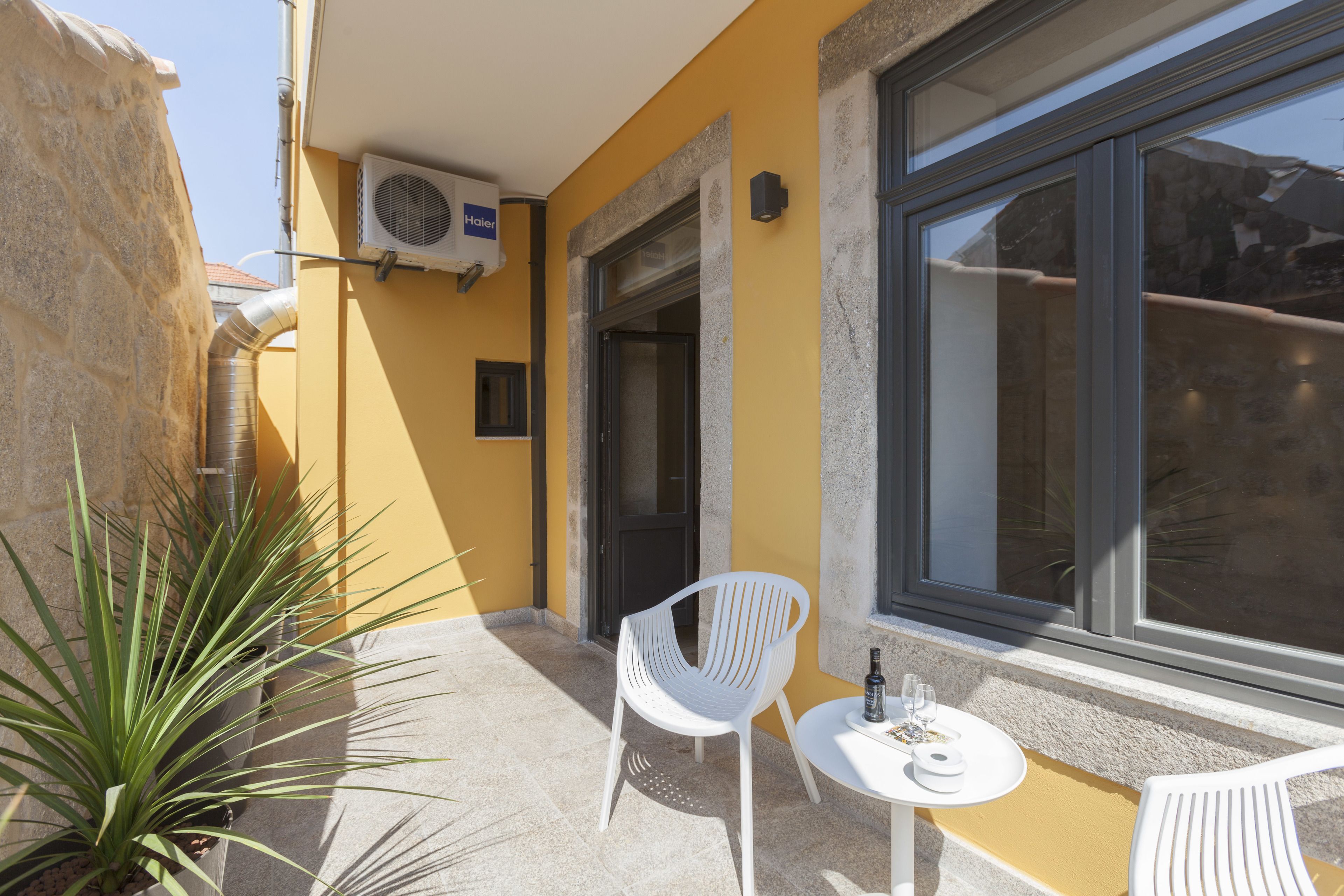 Un edificio amarillo con un gran ventanal, una puerta y una pequeña mesa con sillas.