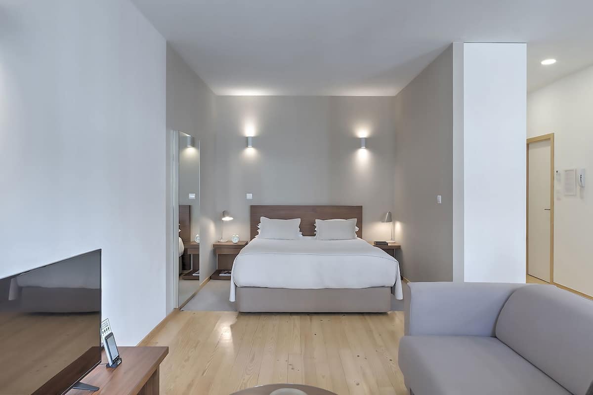 A modern hotel room with a large bed, bedside tables, a desk, and a chair.