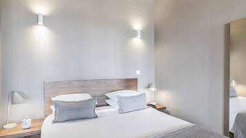 Een keurig opgemaakt hotelkamer met een groot bed, nachtkastjes en wandlampen.