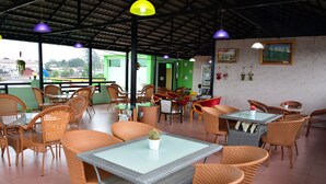 Un comedor interior con mobiliario de mimbre, mesas de vidrio y lámparas colgantes.