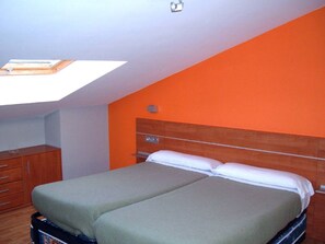 A room with two beds, a wooden headboard, a wooden dresser, and a skylight. - Pardiola Baserria (Hernani)